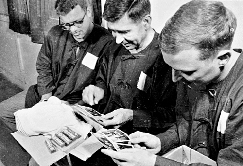  Phi công Walter Eugene Wilber (ở giữa) trong thời kỳ bị giam tại trại giam Hỏa Lò, Hà Nội nhận ảnh và đồ dùng sinh hoạt do gia đình gửi sang