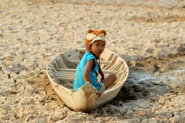 Một bé gái ngồi trên chiếc thuyền trong lòng hồ khô cạn nước do hạn hán ở tình Kandal, Campuchia được phóng viên ghi lại ngày 13/5
